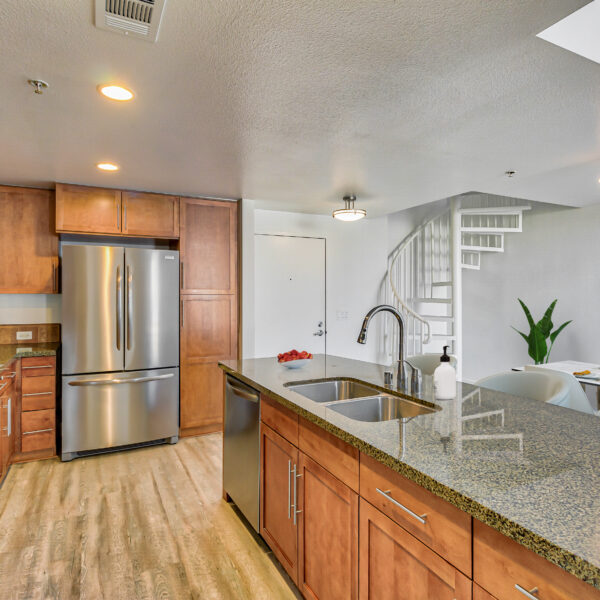 Open floorplan kitchen with stainless steel appliances, granite countertops and modern fixtures